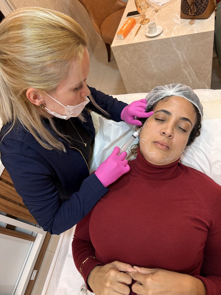 Bruna, enfermeira esteta, aplicando procedimento estético facial com luvas e marcação no rosto da paciente, na Clínica Ornata em Caxias do Sul